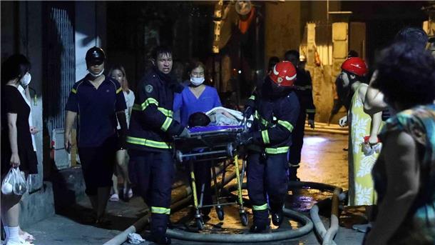 Opferzahl bei Brandkatastrophe in Wohnhaus steigt auf 56 Rettungskräfte tragen eine Person aus dem brennenden Gebäude in Hanoi.