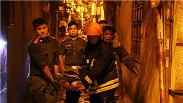 Rettungskräfte tragen eine Person aus einem brennenden Gebäude in der vietnamesischen Hauptstadt Hanoi.