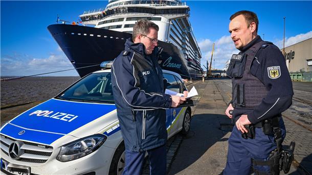 Revierleiter Matthias Kiehn und René Schmidt von der Bundespolizei stehen vor der Mein Schiff 1. Daneben im Columbus Cruise Center wurden soeben die neuen Passagiere kontrolliert.