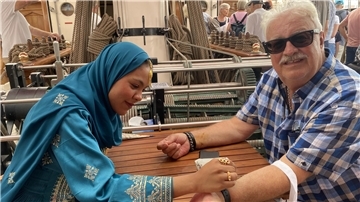 Richard Schwadorf lässt sich von Crew-Mitglied Hooa auf der Shabab Oman II mit Henna etwas auf den Arm schreiben