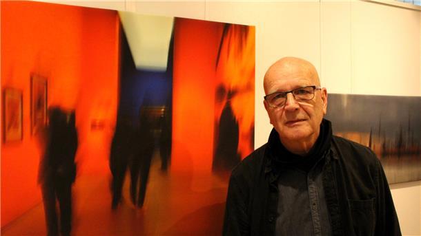 Rolf Engel steht vor einigen seiner ausgestellten Fotografien