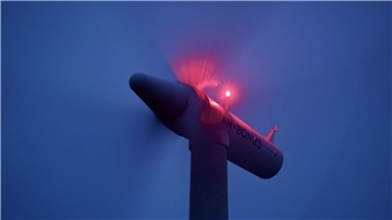 Windkraftrad mit rotierenden Flügeln und blinkenden Lichtern