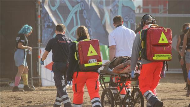 So sind die umliegenden Kliniken auf das Deichbrand-Festival vorbereitet Ein Team von Sanitätern transportiert einen Patienten auf einer Trage über das Festivalgelände