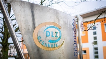 Eine Wand mit hellblau-gelbem Logo DLZ Grünhöfe
