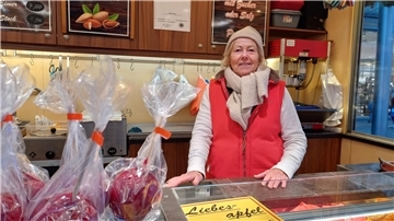 Eine alte Frau verkauft süße Äpfel auf dem Weihnachtsmarkt