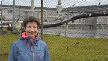 BUND Rotenburg: CCS-Pläne als teure Müllentsorgung? Eine Frau steht vor einem Maschendrahtzaun, der eine Gasförderstation einzäunt.