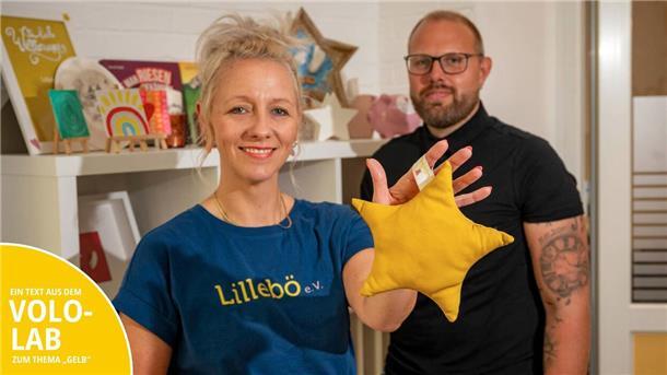 Sabrina Kuiper (li.) und Roman W. (re.) zeigen ein sternenförmiges Kissen, das bei einem der Näh-Events des Vereins Lillebö entstanden ist.