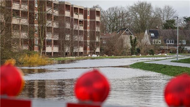 Sandsäcke liegen auf einem durchweichten Deich vor evakuierten Wohnhäusern in Lilienthal bei Bremen.