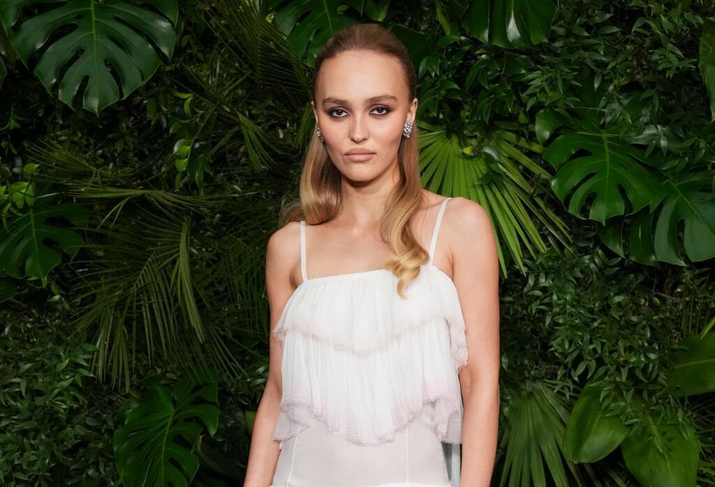 Schauspielerin Lily-Rose Depp schaut in typischer roter Teppich-Pose mit kühler Miene in die Kamera. (Archivbild)