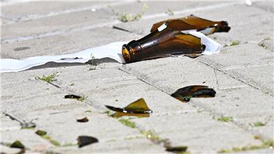 Scherben einer zerbrochenen Bierflasche liegen auf einer gepflasterten Fläche