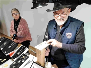 Live erleben: Hobbykünstler zeigen ihr Können in den Markthallen Eine Frau und ein Mann (mit Hut) blicken in die Kamera. Schmuck aus Münzen von Gerhard Belling: Mehr als 60 Aussteller präsentieren in den Markthallen Rodenkirchen kunstvolle Unikate, Dekorationen und Geschenkideen für die Adventszeit.