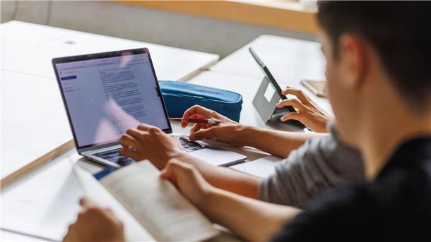 Digitales Arbeiten, KI und Veränderungen für unser Gehirn Schüler eines Gymnasiums sitzen vor einem Computer und benutzen ein KI-Tool.