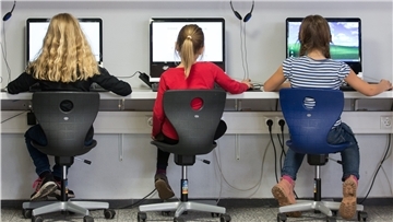 Schülerinnen sitzen in einem Klassenraum einer Grundschule an Computern und arbeiten.