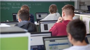 Schülerinnen und Schüler nehmen im Klassenzimmer einer 9. Klasse am Unterricht mit Hilfe von Laptops und Tablets teil.