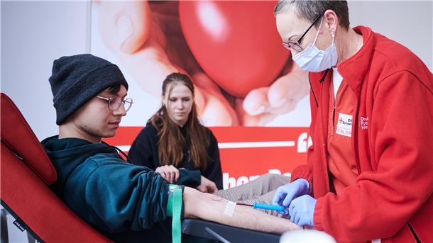 Großereignis wie Fußball-EM wirkt sich negativ auf Blutreserven aus Ein junger Mann spendet Blut. Eine DRK-Mitarbeiterin setzt die Kanüle.