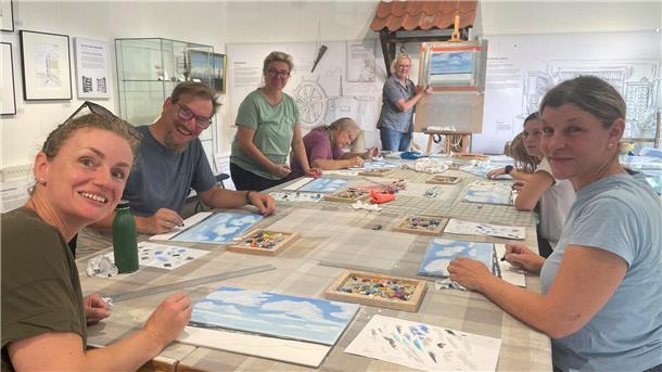 Bilder aus Wolken und Wellen: Butjadingen lockt mit sanfter Pastellmalerei Gruppe sitzt am Tisch und malt.