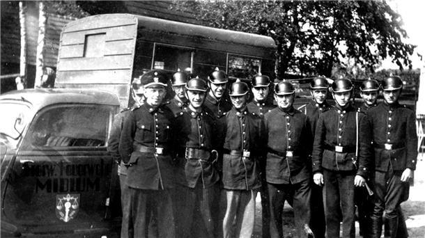 Großes Feuerwehrfest in Midlum: Rückblick auf 125 Jahre Schwarzweißfoto aus der Mitte des 20. Jahrhunderts: Eine Gruppe von Feuerwehrmännern der Freiwilligen Feuerwehr Midlum steht in Uniform und mit Helmen vor einem Einsatzfahrzeug.