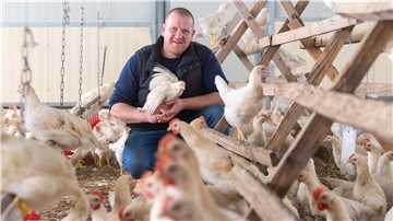 Carsten Bauck, Landwirt, hält ein Hahn aus der Bruderhahn-Initiative in den Händen. 