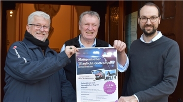 Drei Männer halten ein Plakat