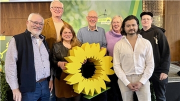 Bild von sieben Personen mit einer großen Sonnenblume in der Mitte