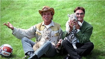 Siegfried (l) und Roy, stellen sich im „Hollywood-Safari-Park" mit zwei weißen Tiger-Jungen den Fotografen vor. Die deutschen Magier sind als „Meister der Illusionen" weltberühmt geworden.