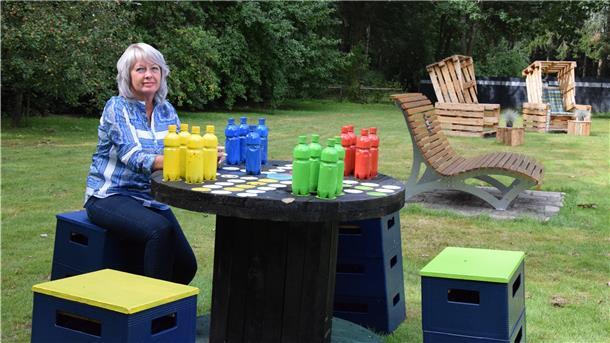 Eine Frau sitzt an einem Tisch mit Spielfiguren.