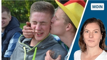 Ein junger Mann küsst einen anderen auf die Wange.