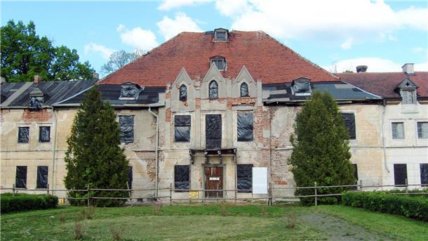 Ein marodes Schloss dessen Fensteröffnungen mit schwarzer Folie verschlossen sind 