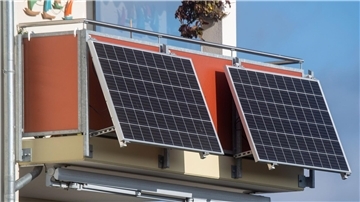 Solarmodule für ein sogenanntes Balkonkraftwerk hängen an einem Balkon.