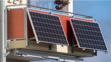 Solarmodule für ein sogenanntes Balkonkraftwerk hängen an einem Balkon.