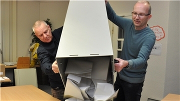Zwei Männer leeren eine Wahlurne