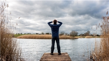 Ein Mann steht vor einem See.