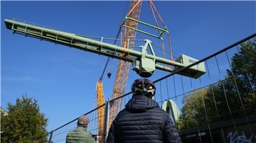Der Ausleger des Rickmerskrans in Bremerhaven wird abgenommen. Schaulustige gucken sich das Spektakel an.