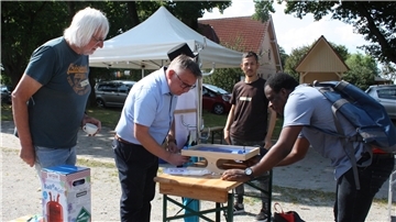 Vier Männer stehen rund um einen Klapptisch, auf dem zwei der Männer eine Partie Magnetfußball spielen.
