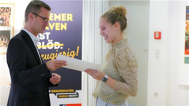 Stadtrat Michael Frost überreicht Bea Hancken die Urkunde für das Lehramtsstipendium. 