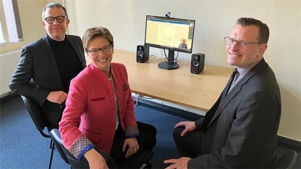 Justiz digital: Bremerhavener können Anträge online einreichen Zwei Herren (links und rechts) lächeln, eine Frau (Mitte) auch. Auf einem Schreibtisch ist ein Bildschirm zu sehen, der eingeschaltet ist. Der Start der Online-Rechtsantragstelle im Arbeitsgericht Bremen-Bremerhaven erleichtert den Bürgern den Zugang zur Justiz, indem sie Anträge und Klagen bequem von zuhause aus einreichen können.