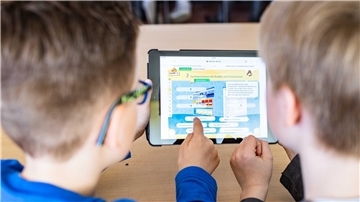 Zwei Schüler arbeiten an einem Tablet.
