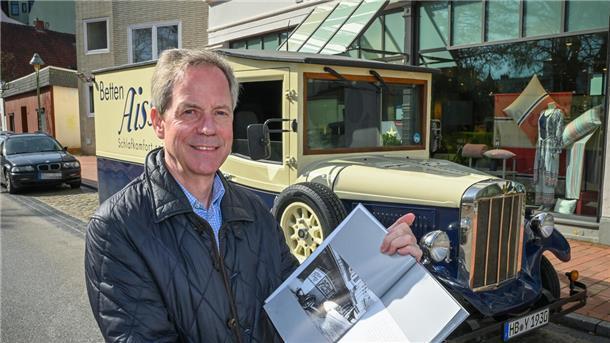Ein Mann steht vor einem Oldtimer.