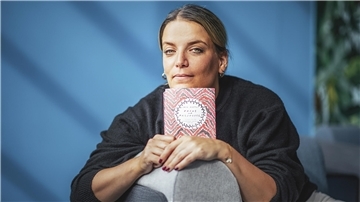 Eine Frau hält ein Buch in der Hand.
