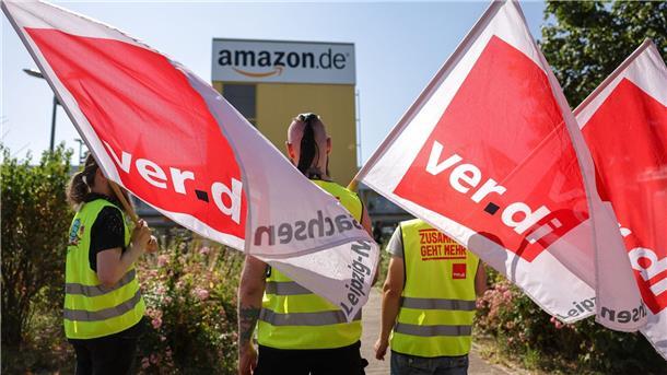 Verdi ruft zum Black Friday zu Warnstreik bei Amazon auf Streikende stehen mit Fahnen von Verdi vor einem Verteilzentrum des Online-Händlers Amazon in Leipzig. (Archivbild)