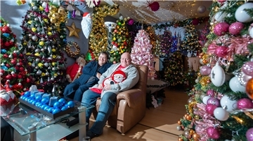 Zwei Menschen in einem Raum mit bunt geschmückten Weihnachtsbäumen.