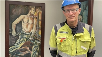 Mann mit Helm neben einer Malerei