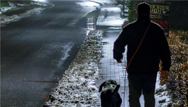 Mann geht mit Hund im Dunkeln Gassi.