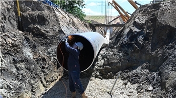 Eine Pipeline wird verlegt. Im Vordergrund ist ein Arbeiter zu sehen.