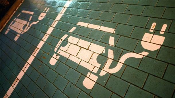 Branchentreffen löst Diskussion um E-Mobilität aus Symbole markieren Parkplätze mit einer öffentlichen Ladesäule für Elektroautos.