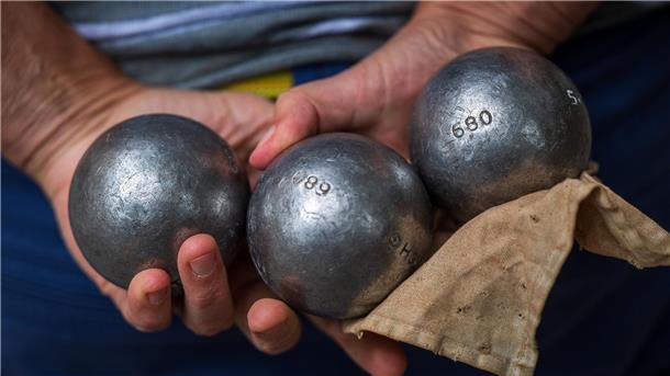 Nordenhamer Betriebssportler bei Weltspielen auf Sizilien erfolgreich Zwei Hände halten drei Boule-Kugeln und ein Tuch.