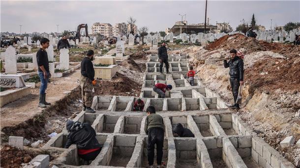 Syrer präparieren entlang der türkisch-syrischen Grenze Gräber für ihre Angehörigen, die bei dem verheerenden Erdbeben ums Leben gekommen sind.