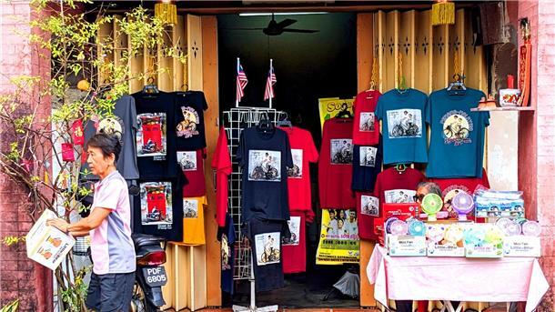 Penangs berühmte Street Art: „Malaysias Antwort auf Banksy“ T-Shirts und andere Dinge, auf denen Street Art-Kunstwerke aus Penang abgebildet sind, werden in einem Geschäft zum Kauf angeboten.