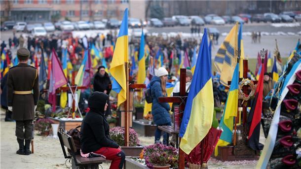 Tag der ukrainischen Streitkräfte: Eine Frau sitzt auf dem Lytschakiw-Friedhof in Lwiw am Grab eines gefallenen ukrainischen Verteidigers.