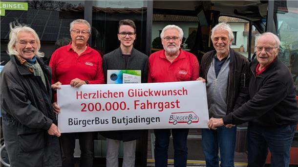 Sechs Männer mit einem Banner. Der Bürger Butjadingen hat den 200.000. Fahrgast begrüßt. 